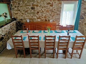 Una mesa de comedor lista con sillas, un jarrón con flores y una botella de vino.