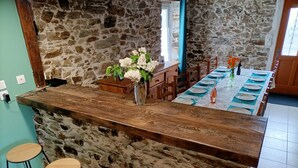 Uma cozinha com parede de pedra, balcão de madeira e banquetas.