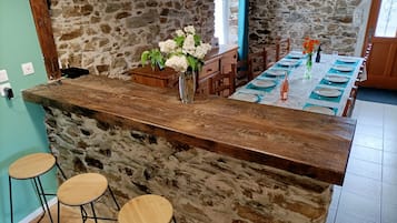 A kitchen with a stone wall, wooden bar counter, and stools.