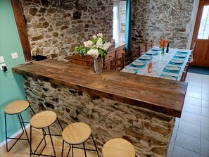 Eine Küche mit Steinwand, einer Holztresore und Hockern.