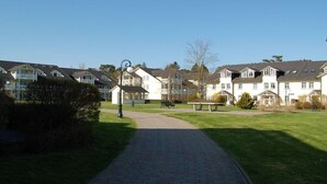 Zona residencial com várias casas de dois andares, um caminho pavimentado e uma pequena área de parque com bancos.