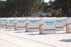 Rows of white beach chairs with 'Dünenpark' printed on them, arranged on a sandy surface. - Holiday apartment with 1 bedroom (Ostseebad Binz)