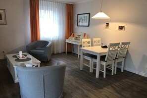 Ein Zimmer mit Esstisch, Stühlen, einer Couch, einem Schreibtisch und einer Lampe.