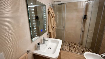 Un bagno con una toeletta, uno specchio illuminato, un box doccia e un bidet.
