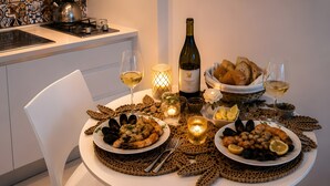 Een eettafel gedekt met zeevruchten, brood en wijnglazen, omringd door kaarsen en een fles wijn.