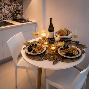 A dining table set with seafood, bread, and wine glasses, surrounded by candles and a bottle of wine. - M.a.g.a. Holiday House in Taormina – Studio with Parking, Sea View, and Self Check-in (Taormina)