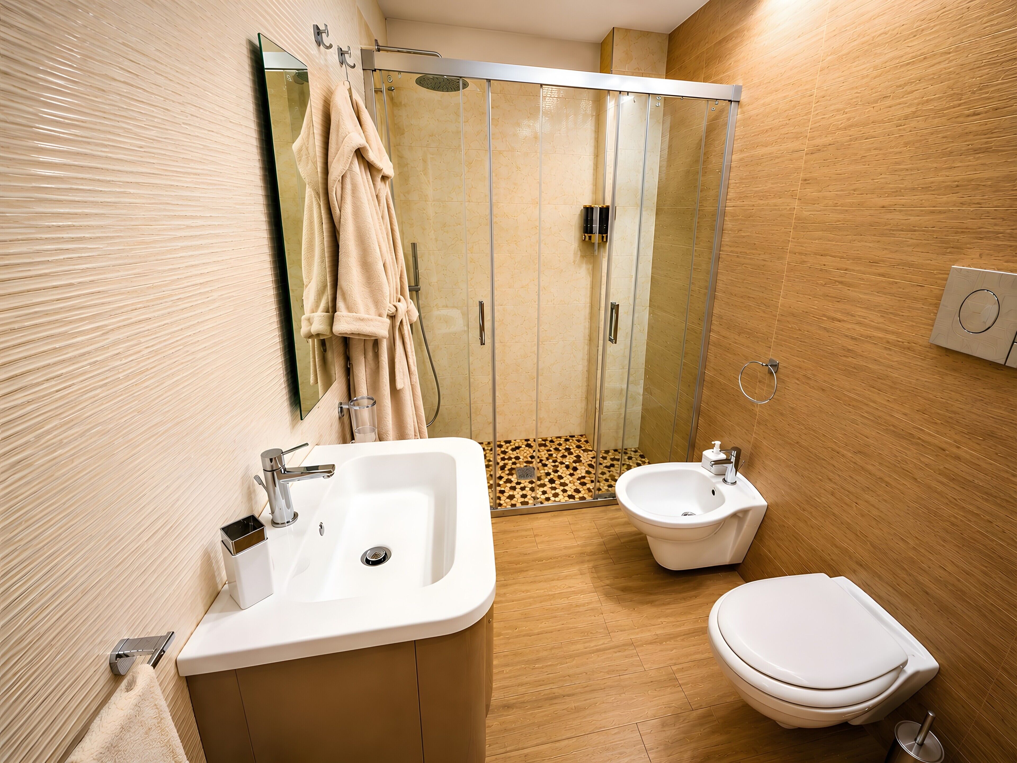 Une salle de bain moderne équipée d’un lavabo, de toilettes, d’un bidet et d’une douche à parois de verre.
