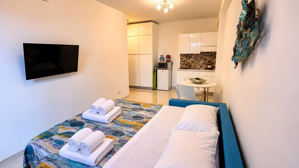 Een hotelkamer met een bed, een televisie, een kitchenette en een eethoek.