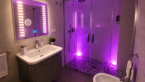 Een moderne badkamer met een wastafel, spiegel en douche.
