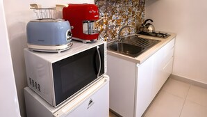 Een kleine keuken met een magnetron, broodrooster en koffiezetapparaat op een aanrecht.