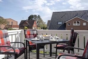 A patio with outdoor furniture, a table set for a meal, and a view of neighboring houses. - Holiday apartment with 1 bedroom (Fehmarn)