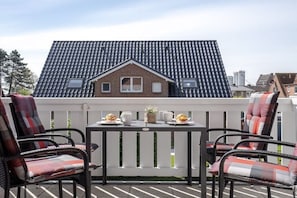 Eine Terrasse mit Tisch und Stühlen, ein Haus im Hintergrund und ein klarer Himmel.