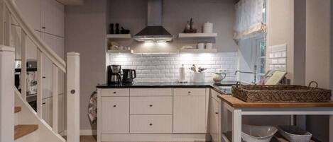 A kitchen with white cabinetry, a black countertop, and a wooden staircase.