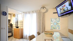 Uma cozinha moderna com área de jantar, televisão na parede e uma tigela decorativa sobre a mesa.