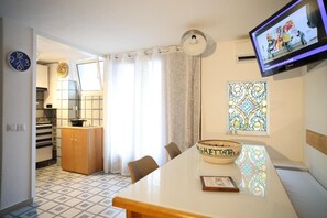 Une cuisine moderne avec un coin repas, un téléviseur fixé au mur et un vase décoratif posé sur la table.