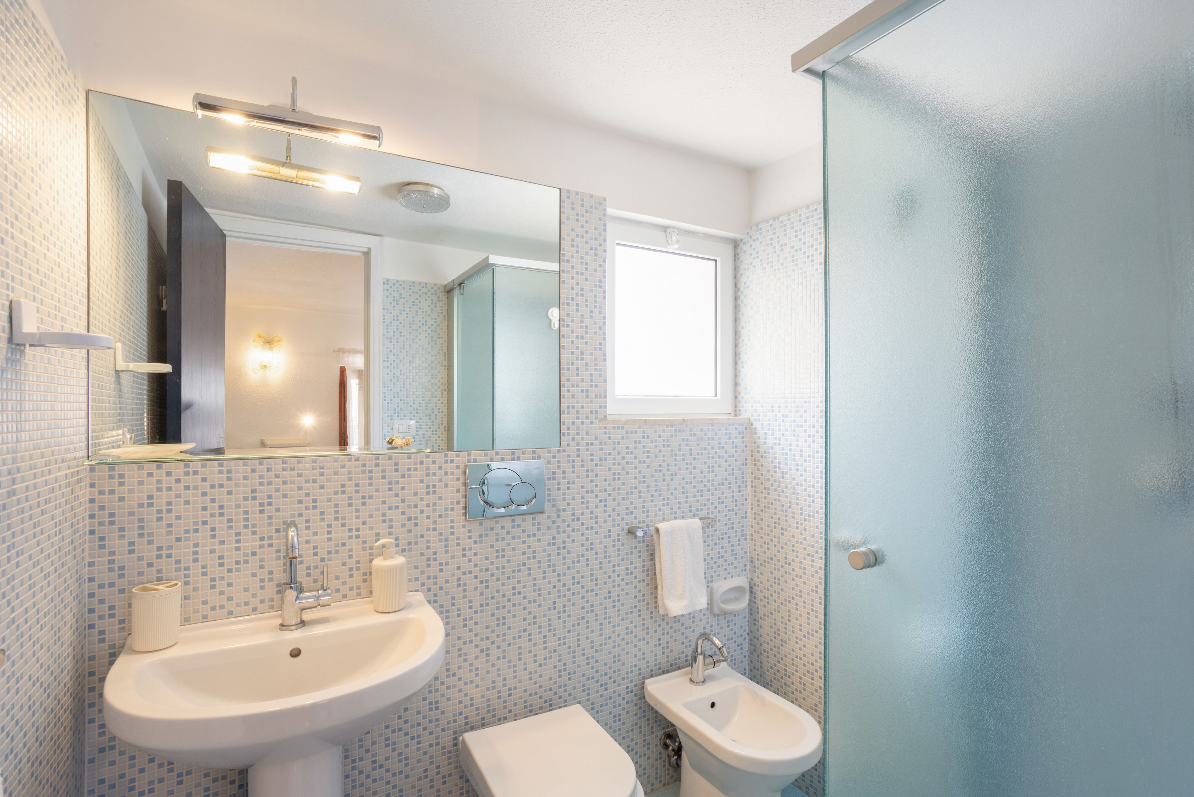 Ein Badezimmer mit Waschbecken, Bidet und einer Duschkabine aus Glas.
