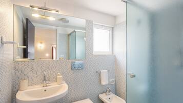 Ein Badezimmer mit Waschbecken, Bidet und einer Duschkabine aus Glas.
