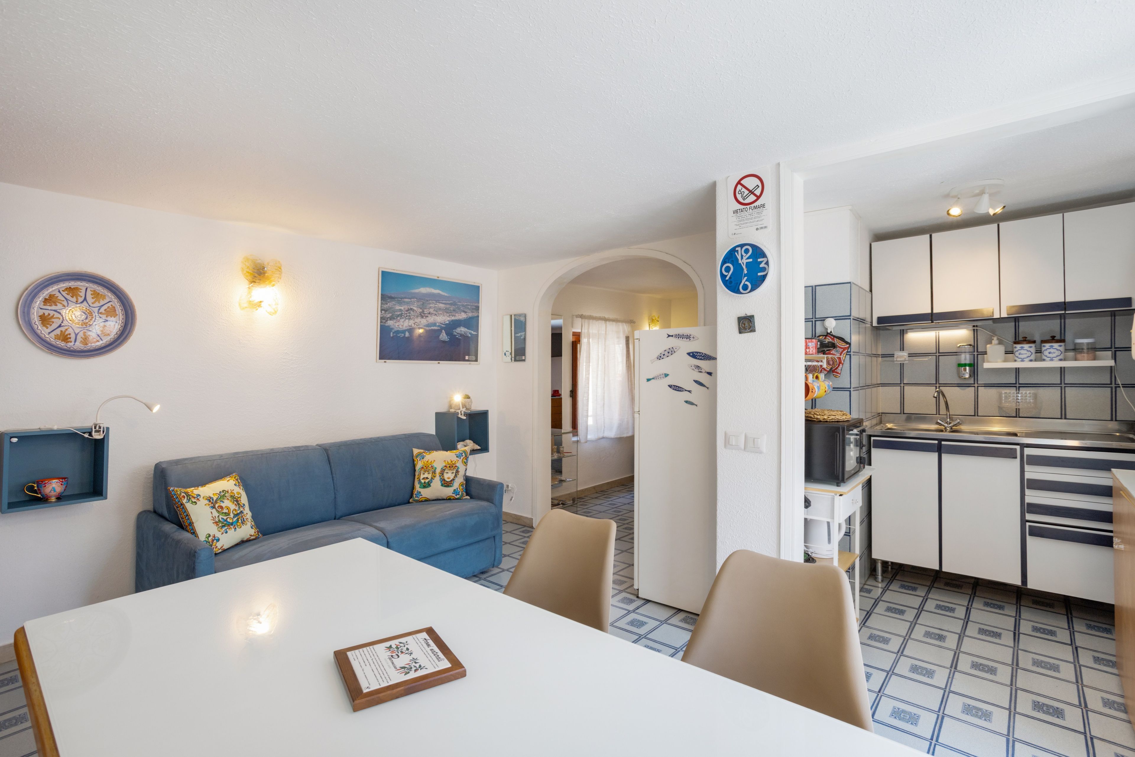 Un espace de vie compact comprenant un coin repas, une kitchenette et un canapé agrémenté de coussins décoratifs.