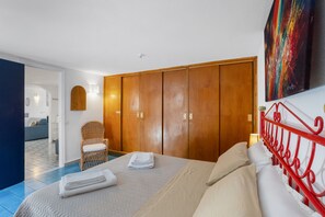 A hotel room with a bed, a wooden wardrobe, a chair, and a painting on the wall. - Agatella's House Apartment with Sea View, Private Terrace, and Air Conditioning (Aci Castello)