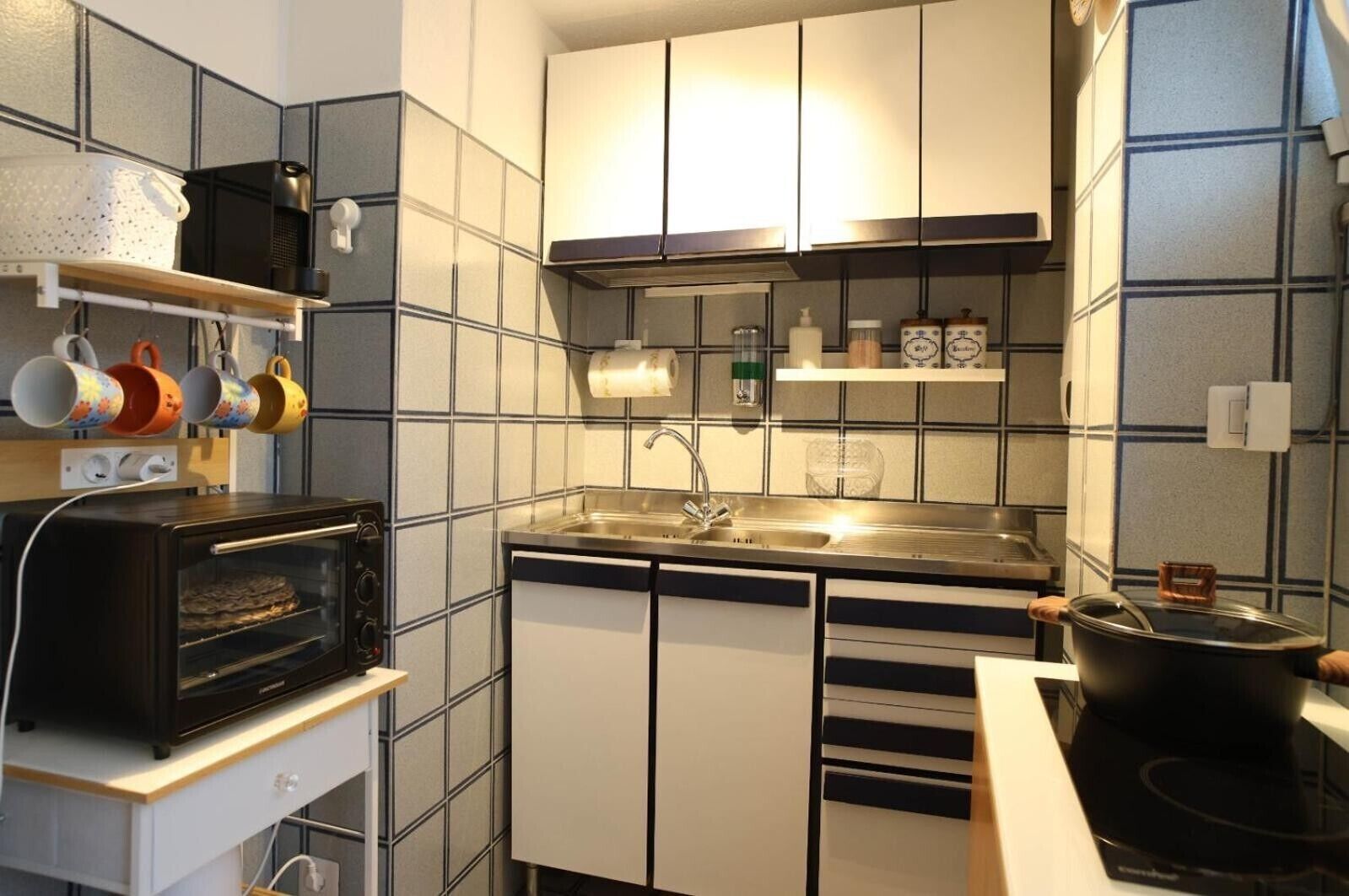 A compact kitchen with a built-in oven, a sink, and a stove.