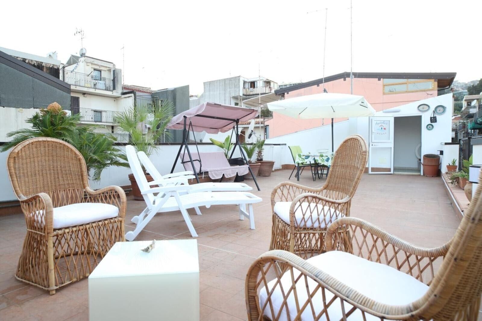 A rooftop terrace with wicker furniture, including chairs and a table, and a swing set.