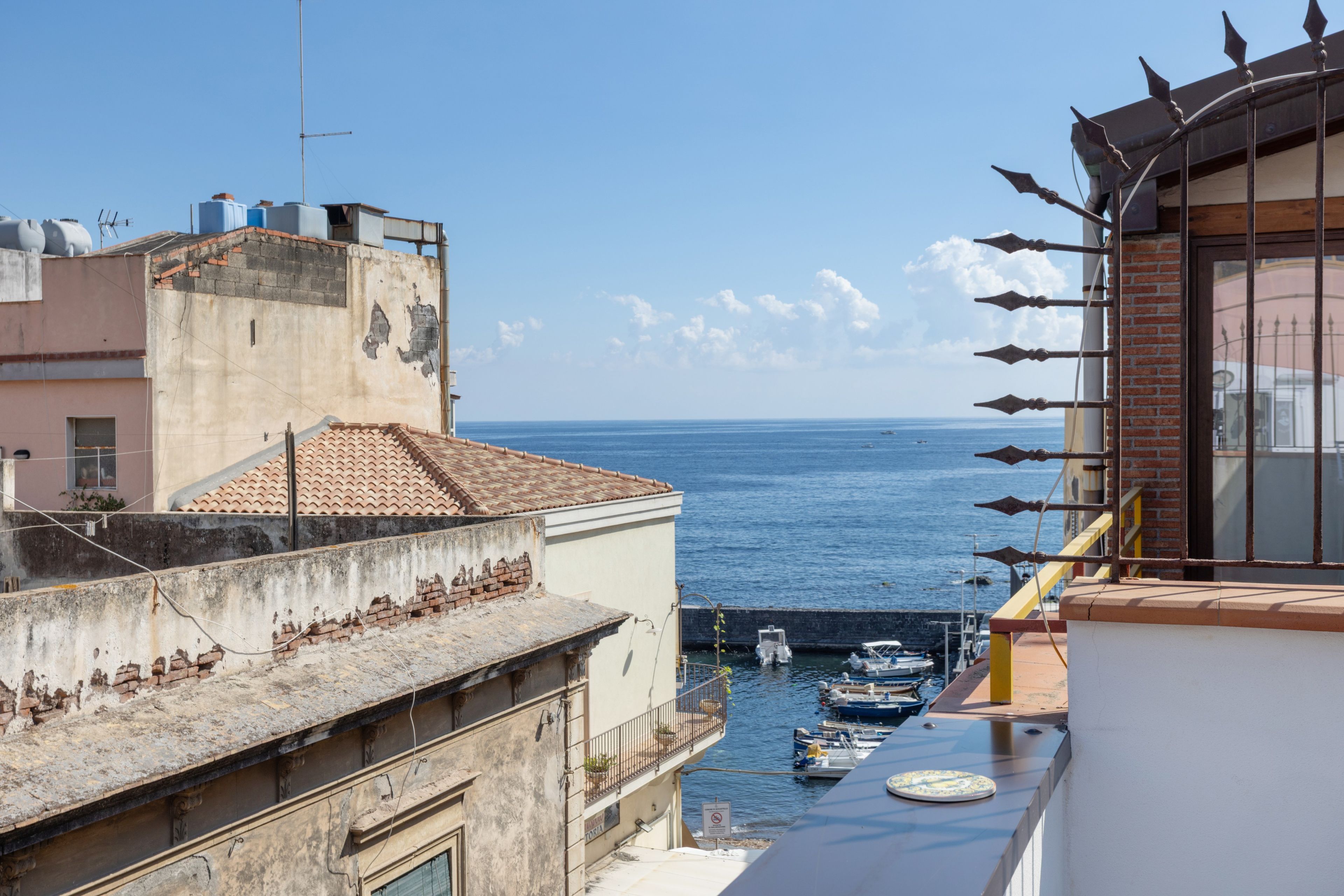 Un bâtiment situé sur la côte, avec vue sur la mer, doté d’un balcon avec une balustrade, et un petit bateau amarré à proximité.