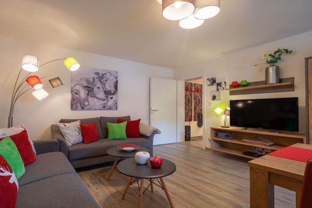 Una sala moderna con sofá, mesa de centro y televisor de pantalla plana.