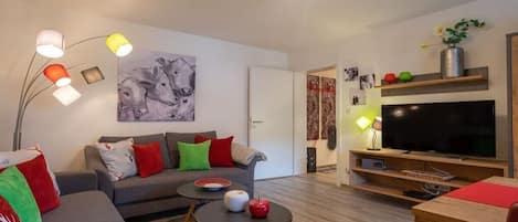 Una sala moderna con sofá, mesa de centro y televisor de pantalla plana.