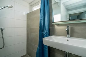 Ein Badezimmer mit Dusche, Waschbecken und Spiegel.