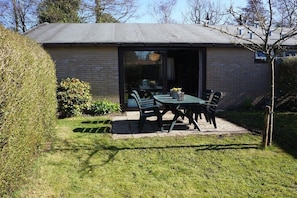 Ein Haus mit einer Terrasse, einem Tisch und Stühlen.