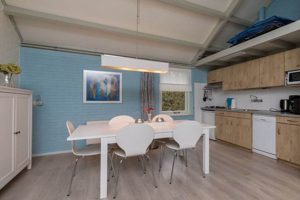 Eine moderne Küche mit weißen Schränken, einem Esstisch mit Stühlen und einer Pendelleuchte.
