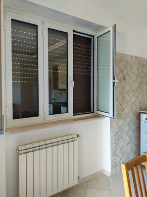 Ein Zimmer mit Fenster, Heizkörper und gefliesten Wänden.