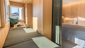 Una habitació amb un llit, una finestra i zona de seients amb coixins.