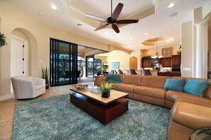 Ein geräumiges Wohnzimmer mit einem großen Sofa, einem Couchtisch und einem Deckenventilator.