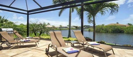Un espace extérieur abrité avec des fauteuils confortables et un barbecue.