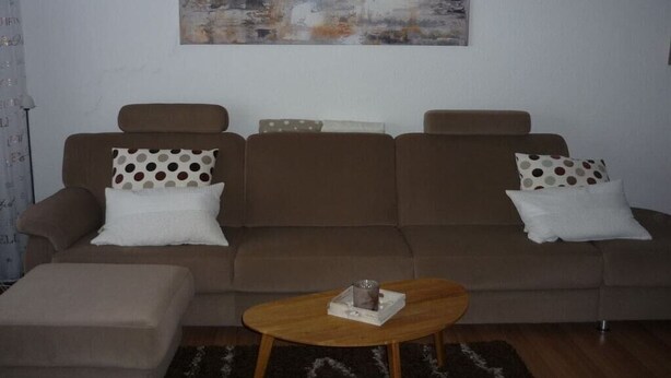 Uma sala de estar com sofá, mesa de centro e um quadro na parede.