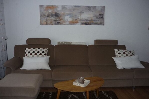 A living room with a sofa set, a coffee table, and a painting on the wall. - Holiday apartment with 1 bedroom (Dornumersiel)