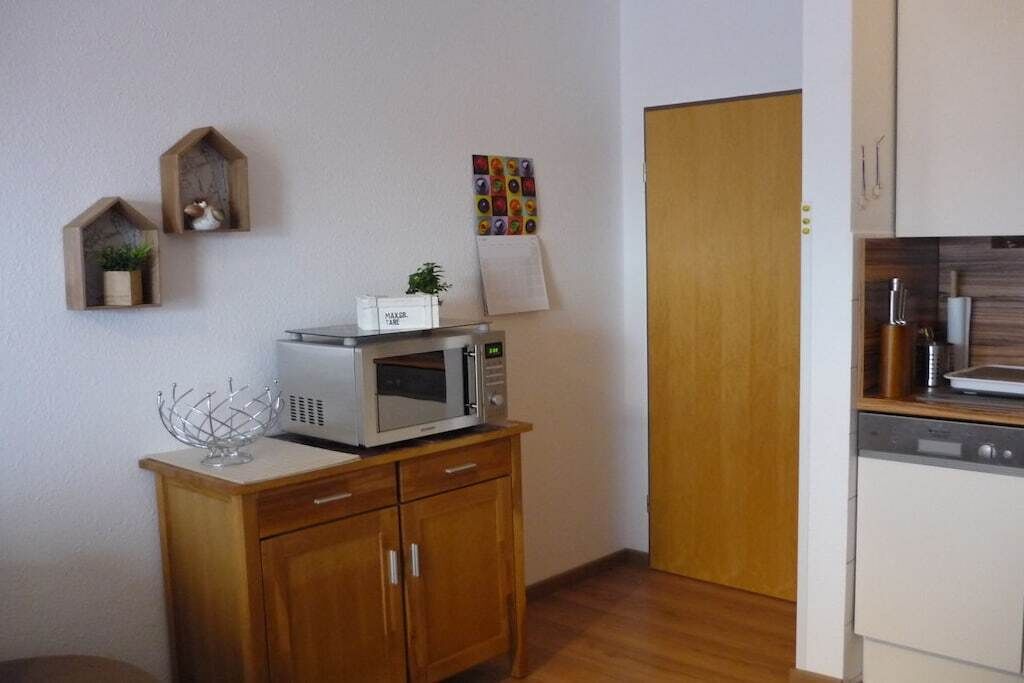 Une cuisine compacte avec un micro-ondes posé sur un meuble en bois, une petite plante et un élément de décoration murale aux couleurs vives.