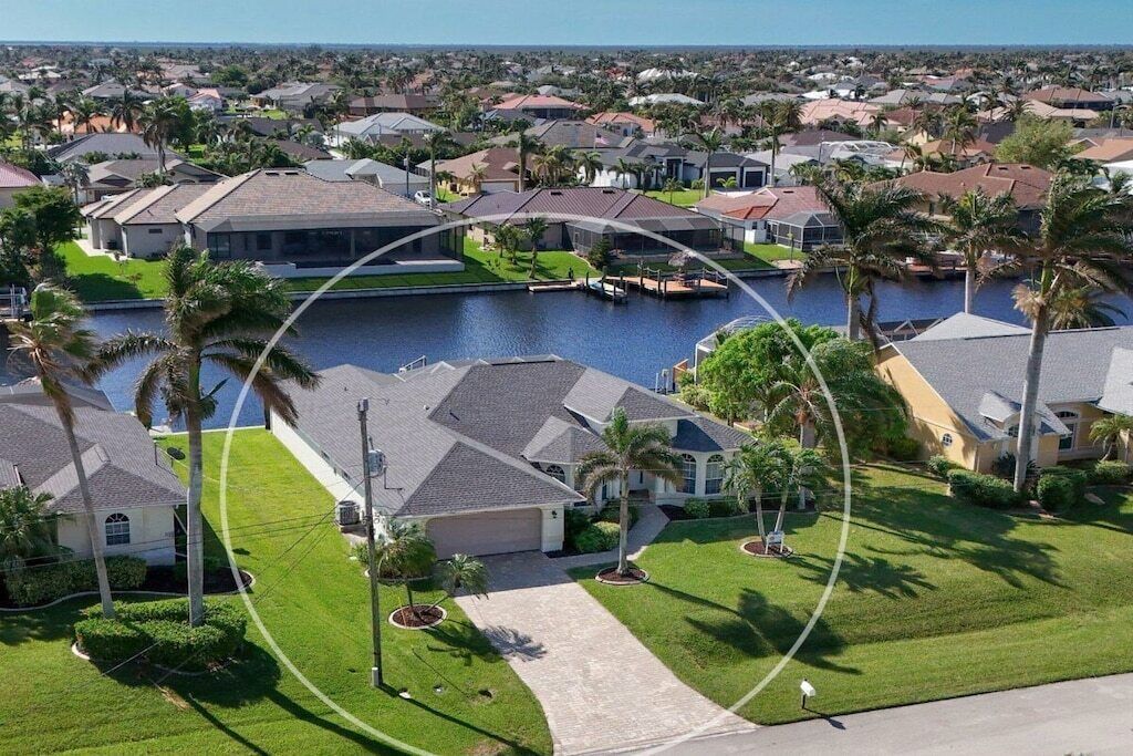 A residential area with houses, a canal, and palm trees.
