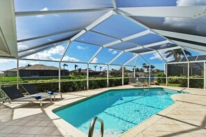 A covered swimming pool with lounge chairs and a view of the surrounding area. - CCVS - Villa Tuscany with boat dock (Cape Coral SW FL)