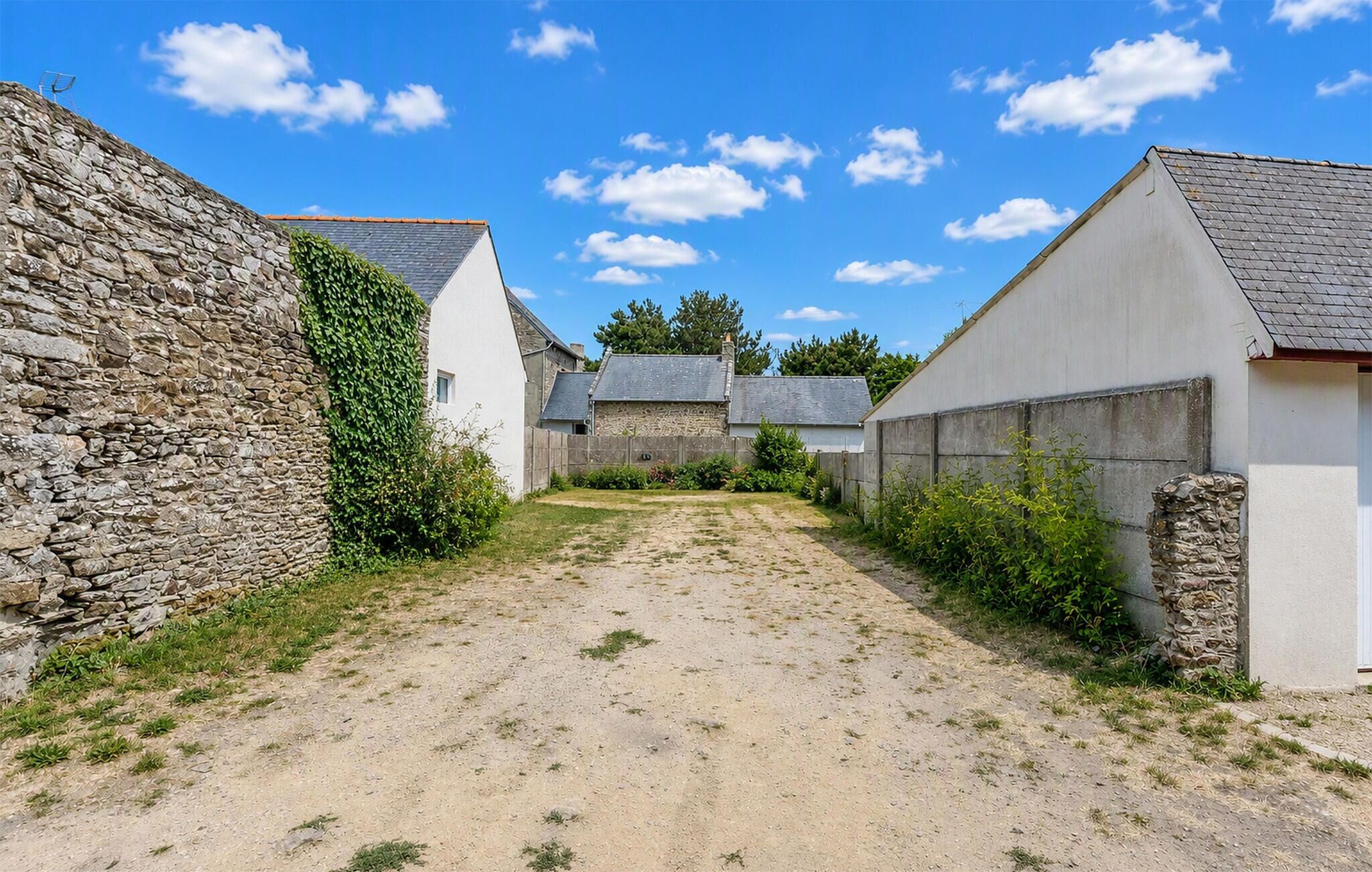 A narrow alleyway between stone and white buildings with a clear sky above.