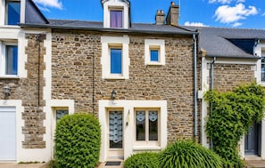 A stone facade building with a symmetrical design, featuring a central entrance with a door and windows on either side. - Nice home in Cancale with WiFi (Cancale)