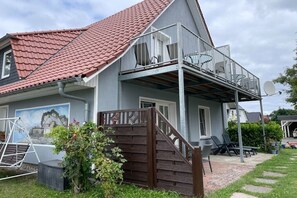 A two-story house with a red-tiled roof, a balcony with chairs, and a satellite dish. - holiday home at the harbor (Zingst)