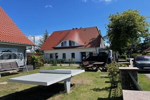 A residential property with a red-tiled roof, a white exterior, and a front yard with a bench and a picnic table. - holiday home at the harbor (Zingst)