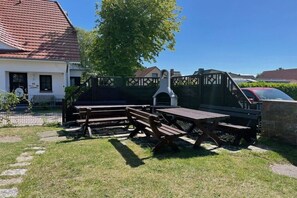 An outdoor seating area with picnic tables and benches, a barbecue grill, and a stone wall. - holiday home at the harbor (Zingst)