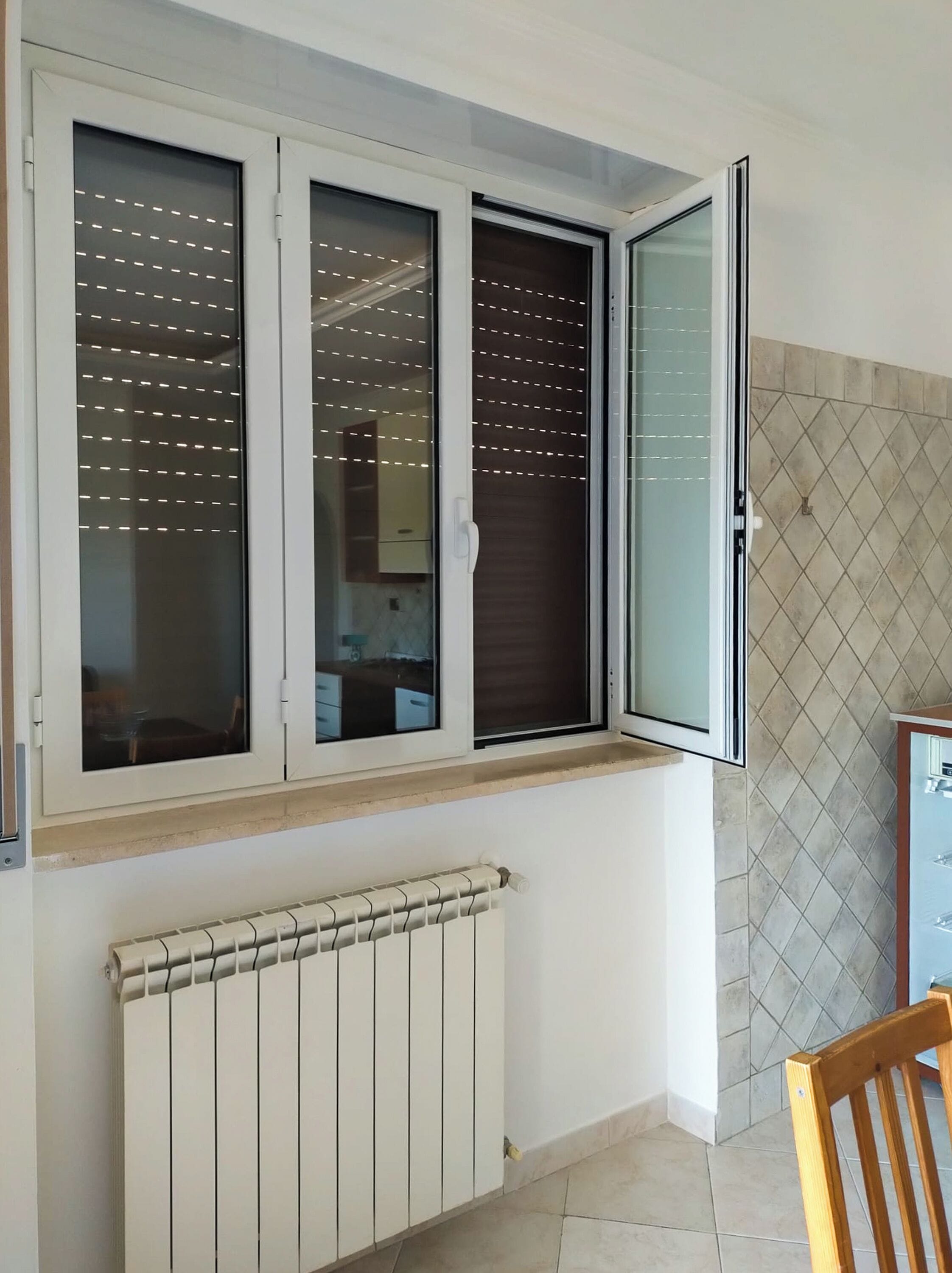 A room with a window, a radiator, and a tiled wall.