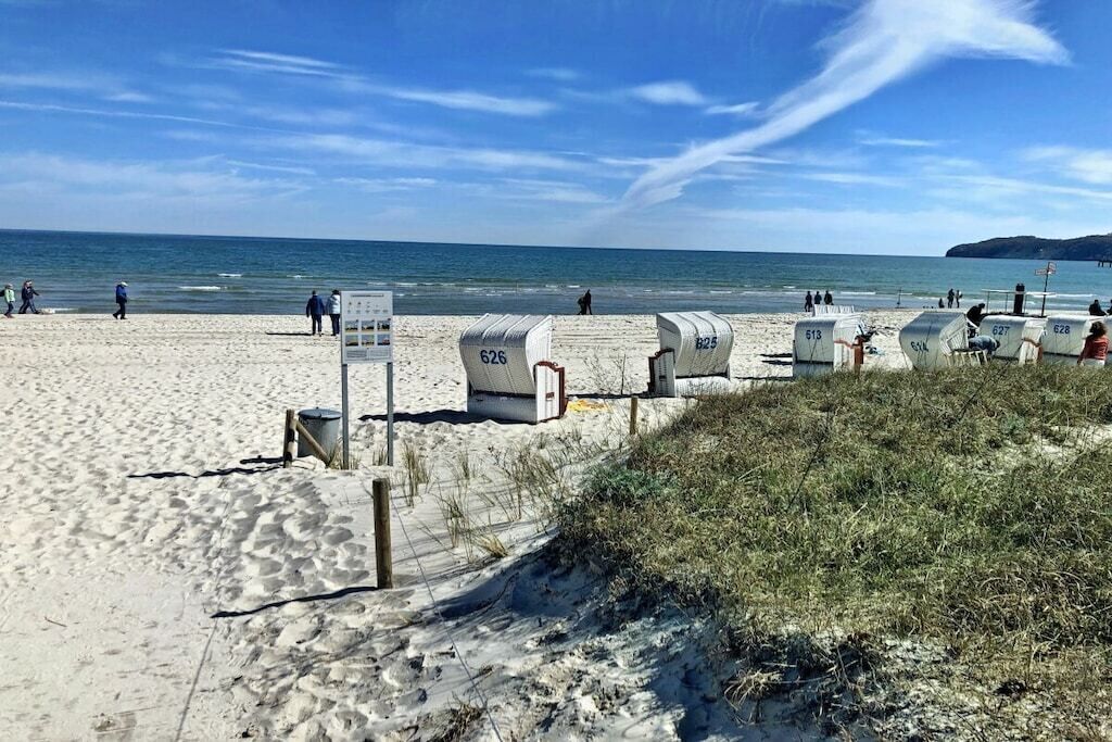 En strand med nummererede strandhuse og kig til havet.