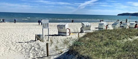 En strand med nummererede strandhuse og kig til havet.