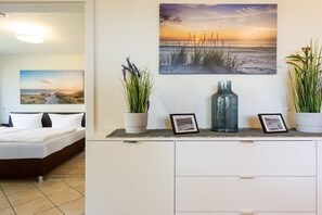 A bedroom with a bed, a nightstand, a dresser, and two wall-mounted pictures. - Anchorage - Binz Stars (Ostseebad Binz)