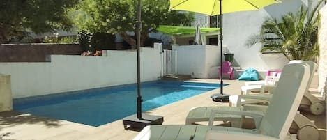A swimming pool with lounge chairs and a yellow umbrella.